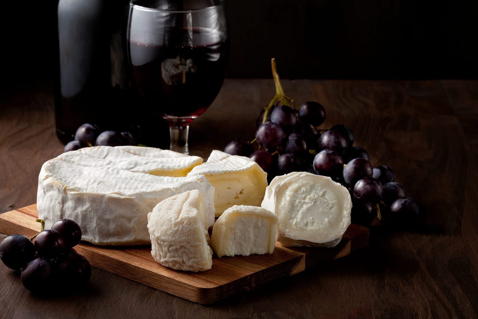 Variety of different cheese with wine and fruits.